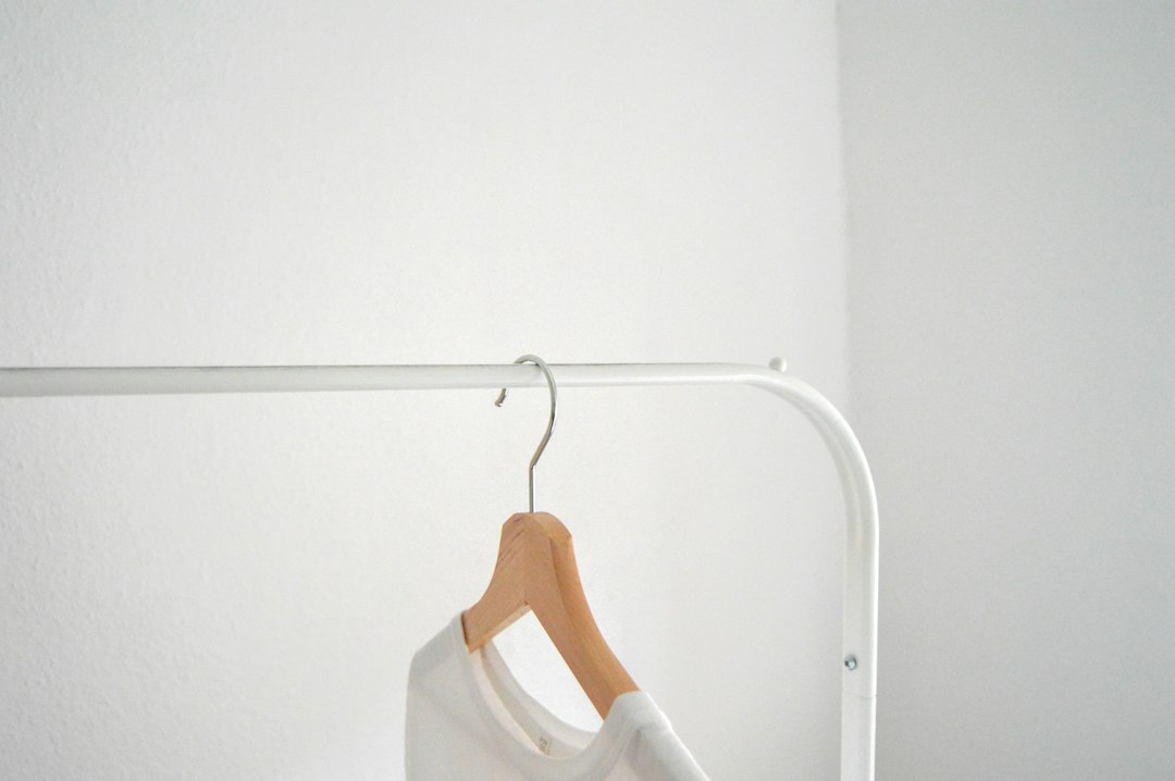 Illustrated capsule wardrobe for women on a minimalist clothing rail with neutral tops, trousers, dresses, layers, and shoes arranged to mix and match